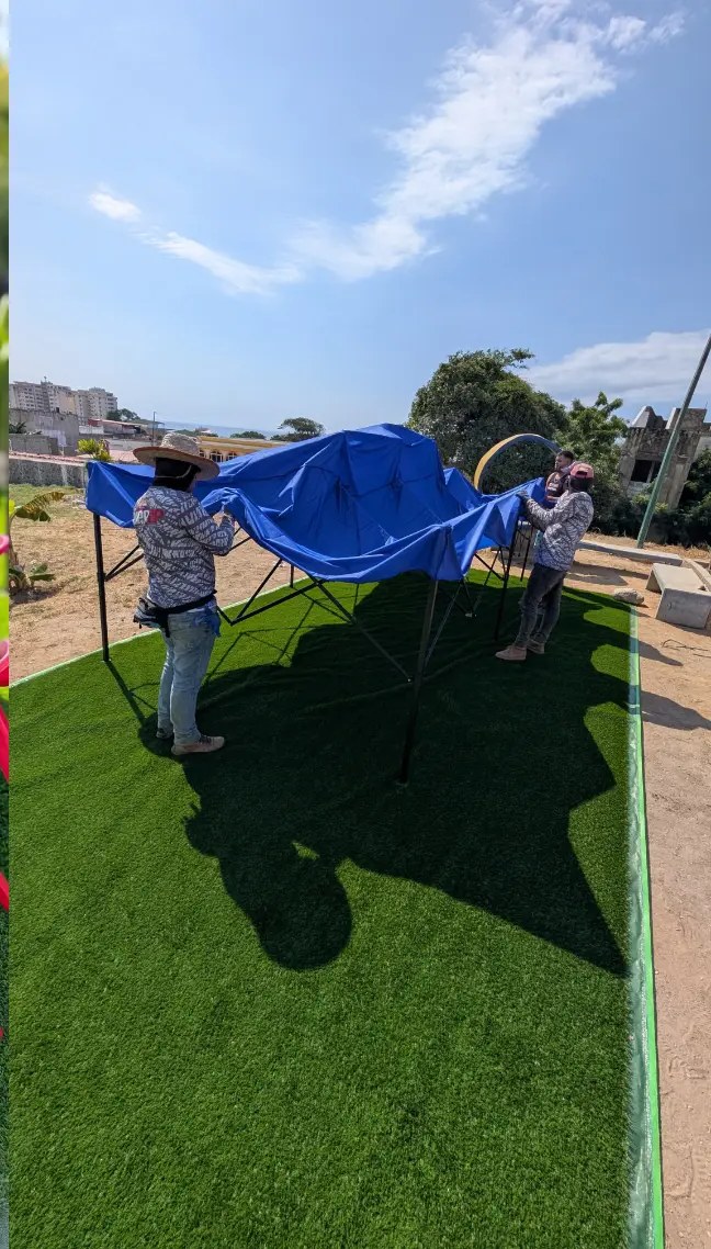 Dos vecinos montando la estructura del toldo azul en el terreno