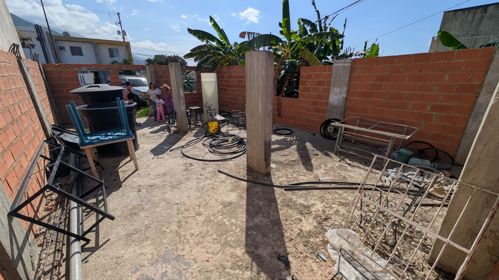 Terreno cercado con paredes de bloque rojo y columnas donde puede construirse la escuela
